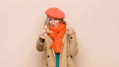 Yaşlı ya da orta yaşlı, güzel bir kadın kamerayı iki parmağıyla ve kızgın bir ifadeyle sana görevini yapmanı söylüyor.