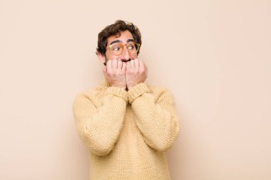 Genç havalı adam endişeli, gergin, stresli ve korkmuş görünüyor, tırnaklarını yiyor ve düz duvara karşı yanal fotokopi alanı arıyor.