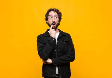 Şaşırmış, gergin, endişeli ya da korkmuş bakışları olan genç, çılgın yakışıklı adam, turuncu duvara karşı fotokopi odasına bakıyor.