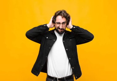 Genç çılgın yakışıklı adam hayal kırıklığına uğramış ve sıkılmış hissediyor, başarısızlıktan bıkmış ve bıkmış, turuncu duvara karşı sıkıcı, sıkıcı görevlerden bıkmış