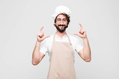 Genç aşçı çerçeveledi ya da iki eliyle kendi gülümsemesini özetledi. Olumlu ve mutlu görünüyordu. Beyaz duvara karşı sağIık kavramı.
