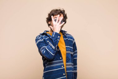 Genç çılgın adam şok olmuş, korkmuş ya da dehşete düşmüş görünüyor. Yüzü elle kaplanmış ve parmaklarının arasından düz duvara bakıyor.