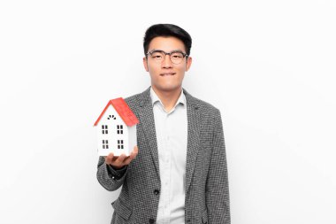 Genç Japon adam şaşkın ve şaşkın görünüyor, gergin bir hareketle dudaklarını ısırıyor, ev modelinin sorununun cevabını bilmiyor.