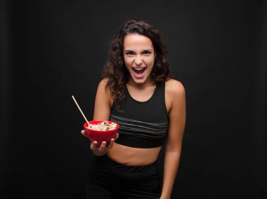 Genç ve güzel bir kadın sinirli, sinirli ve hayal kırıklığına uğramış görünüyor. Kahvaltıda sağlıklı bir kase yemenin nesi yanlış? 