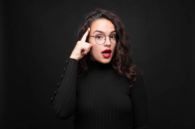 Genç, güzel bir kadın şaşırmış, ağzı açık, şok olmuş, siyah arka plana karşı yeni bir düşünce, fikir ya da konsept keşfediyor..