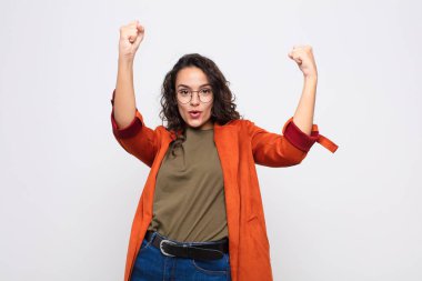 Genç ve güzel bir kadın inanılmaz bir başarıyı kutluyor. Kazanan gibi, heyecanlı ve mutlu görünüyor. Al bakalım! Beyaz duvara yaslan