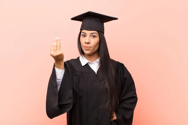 young latin woman student making capice or money gesture, telling you to pay your debts!