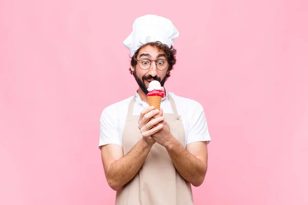 young crazy chef man with an ice cream against pink wall