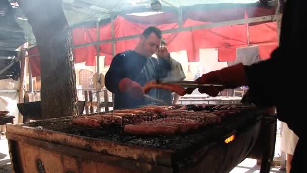 Ludzie gotują mięsa i kiełbasy na ogień na ulicy podczas Medieval festival w Montblanc, Hiszpania. — Wideo stockowe