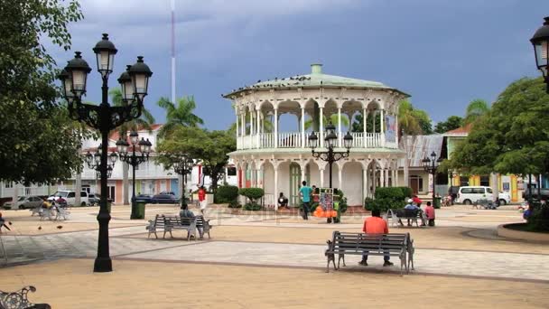 Lidé odpočívají na centrálním náměstí v městečku Puerto Plata, Dominikánská republika. — Stock video