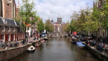 Amsterdam, Hollanda arka planda Katedrali'nde ile kanal tarafından insanlar yürümek.