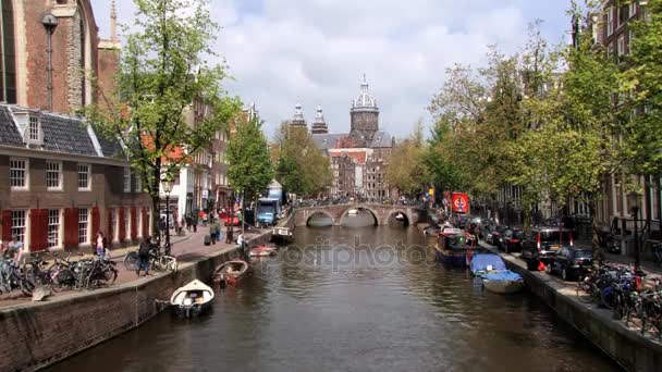 Mensen lopen door het kanaal met een kathedraal op de achtergrond in Amsterdam, Nederland. — Stockvideo