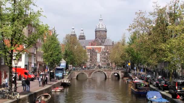 Mensen lopen door het kanaal met een kathedraal op de achtergrond in Amsterdam, Nederland. — Stockvideo