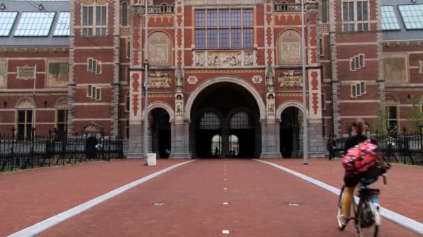 As pessoas andam de bicicleta em frente ao edifício do Rijksmuseum em Amsterdã, Países Baixos . — Vídeo de Stock