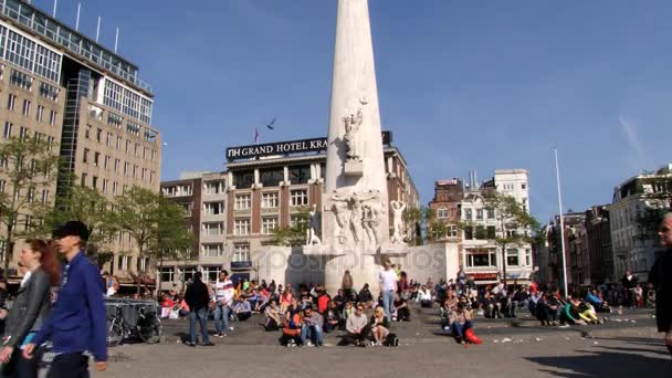 Люди идут по площади перед национальным памятником "Дамба" в Амстердаме, Нидерланды . — стоковое видео