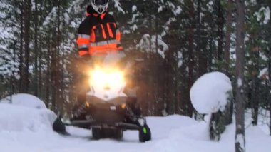 Turistler kış orman tarafından kar motosikletleri binmek iz Inari, Finlandiya.