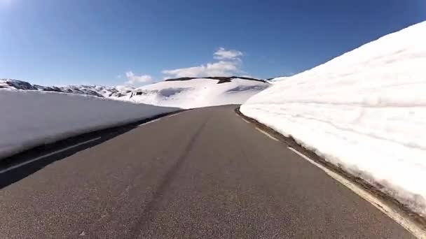 Rijdende auto door een bergweg van het platteland met sneeuw muren aan de zijkanten in Noorwegen. — Stockvideo