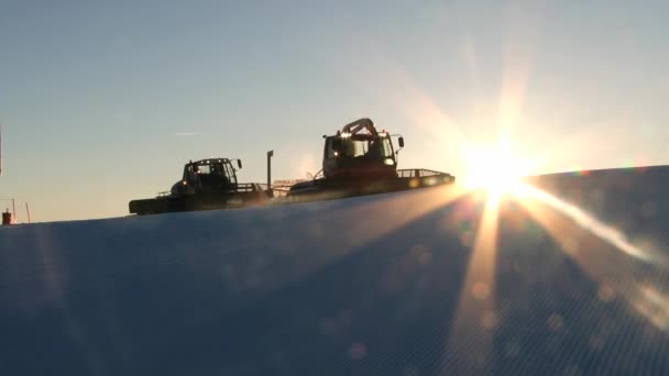 Människor driva snowcat maskiner förbereder skidbackarna vid solnedgången i Trysil, Norge. — Stockvideo