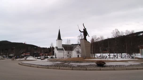 Visa att skidåkare statyn med kyrkan i bakgrunden i Trysil, Norge. — Stockvideo