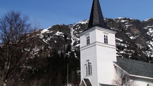 Cars pass by the road in front of the church in Hemsedal, Norway. — Stock Video