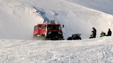 İnsanlar sürücü kırmızı snowcat araç Spitsbergen (Svalbard) adalar şehir Longyearbyen, Norveç yakınındaki dağlarda kutup karda.