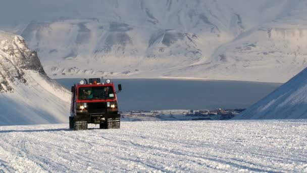 Lidé řídit vozidlo červené rolba na arktický sníh v horách souostroví Špicberky (Svalbard) poblíž města Longyearbyen, Norsko — Stock video