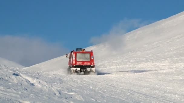 사람들이는 Spitsbergen (스발바르) 열도 롱위에아르뷔엔, 노르웨이의 마을 근처의 산에서 북극 눈에 붉은 snowcat 차량을 운전합니다 — 비디오