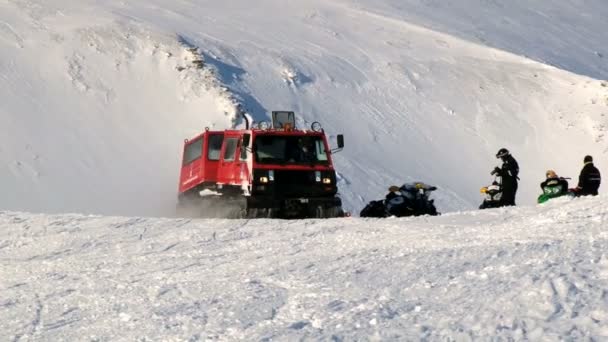 사람들이는 Spitsbergen (스발바르) 열도 롱위에아르뷔엔, 노르웨이의 마을 근처의 산에서 북극 눈에 붉은 snowcat 차량을 운전합니다. — 비디오