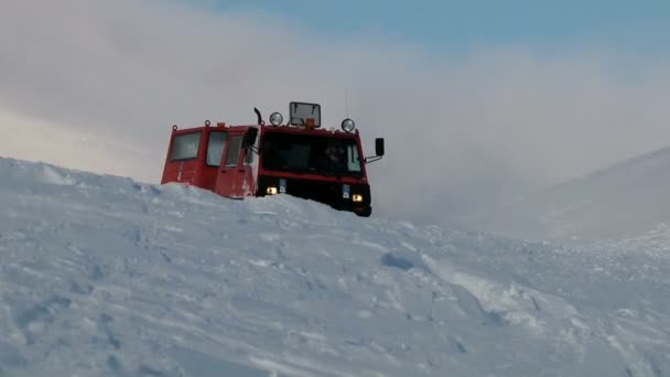 사람들이는 Spitsbergen (스발바르) 열도 롱위에아르뷔엔, 노르웨이의 마을 근처의 산에서 북극 눈에 붉은 snowcat 차량을 운전합니다. — 비디오