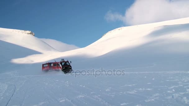 Az emberek meghajtó piros snowcat jármű a sarkvidéki hó a hegyekben, a Spitzbergák (Svalbard) szigetcsoport közelében a város Longyearbyen, Norvégia. — Stock videók