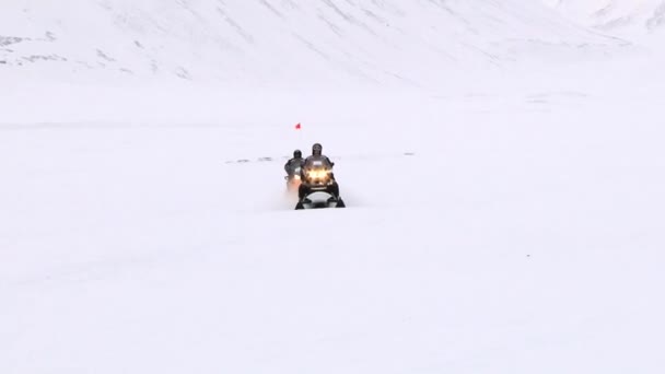 La gente monta motos de nieve en el asentamiento ártico de Longyearbyen, Noruega . — Vídeos de Stock