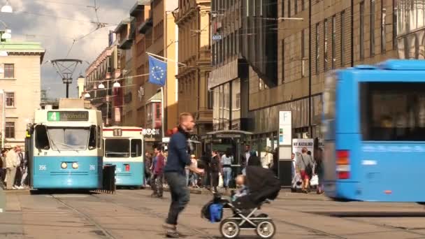 Ludzie przejść przez ulicę, obok przystanek komunikacji miejskiej w Göteborgu, Szwecja. — Wideo stockowe