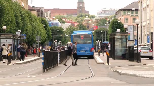 Mensen steek straat bij de halte van het openbaar vervoer in Göteborg, Zweden. — Stockvideo