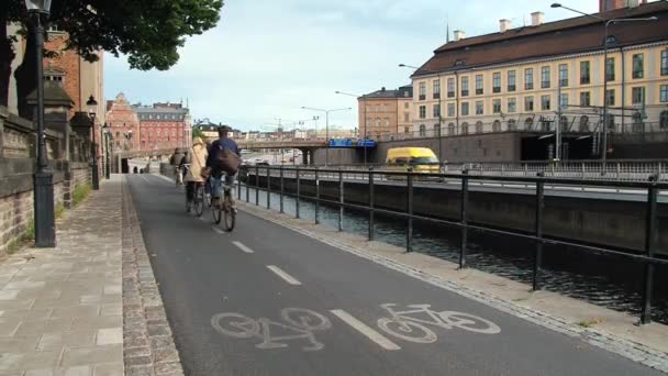 Lidé jezdí na kole v pruhu pro cyklisty na straně kanálu v Stockholm, Švédsko. — Stock video