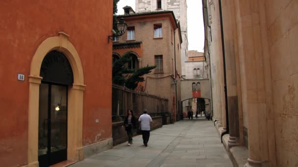 Människor går genom gatan med romansk Ghirlandina klocktornet i Modena katedralen i bakgrunden i Modena, Italien. — Stockvideo