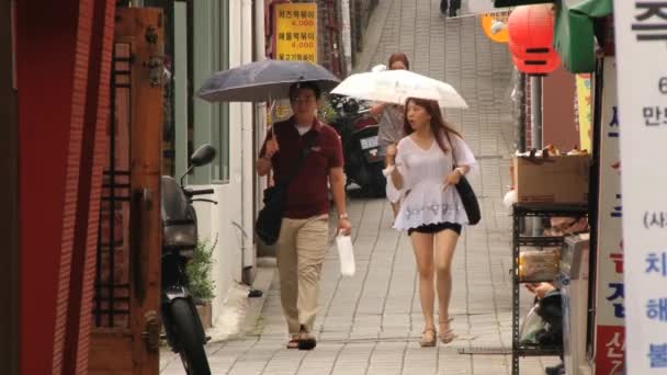 Asiaten spazieren mit Regenschirmen durch die insadon street in seoul, Korea. — Stockvideo