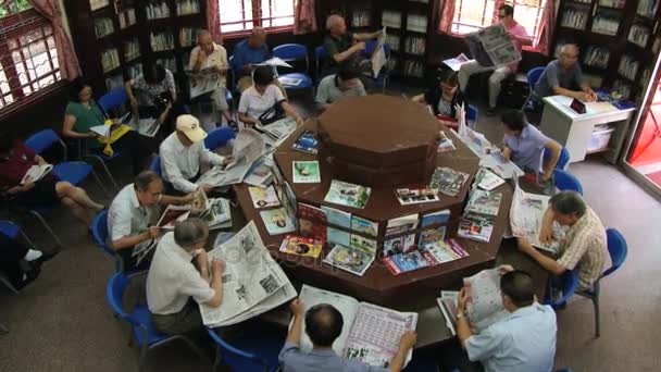La gente lee periódicos en una biblioteca pública en Macao, China. Vista desde arriba . — Vídeo de stock