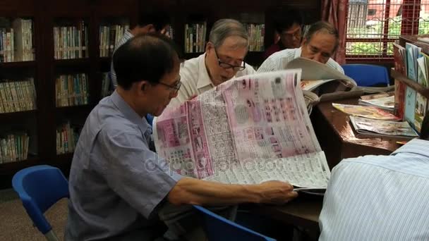 Männer lesen Zeitungen in einer öffentlichen Bibliothek in Macau, China. — Stockvideo