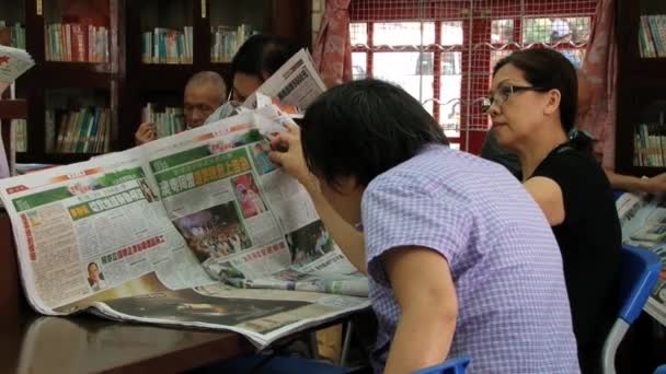 Folk läser dagstidningar i ett offentligt bibliotek i Macau, Kina. — Stockvideo