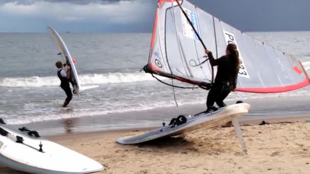Lidé přinášejí prkna na windsurfing na břeh v Sopoty, Polsko. — Stock video