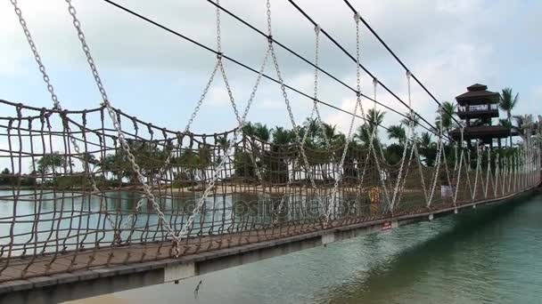 Une personne marche à pied par le pont suspendu de la plage de Palawan à l'île de Sentosa, Singapour . — Video