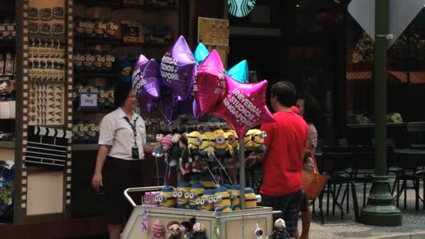 Kvinna säljer ballonger och souvenirer på temaparken Universal studio på Sentosa island, Singapore. — Stockvideo