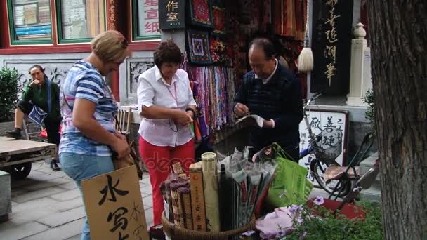 Toeristen kopen souvenirs bij een straat winkel in Peking, China. — Stockvideo