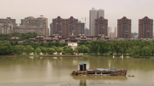 시안, 중국의 Datang 푸 롱 정원에서 물 건너 도시의 현대 주거 건물에 보기. — 비디오