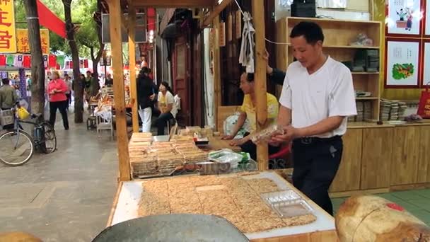 Ο άνθρωπος πακέτα γλυκά στο στάβλο σε μια αγορά τροφίμων δρόμου στο Xian, Κίνα. — Αρχείο Βίντεο