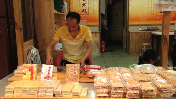El hombre empaca dulces en el puesto de un mercado callejero de alimentos en Xian, China . — Vídeo de stock