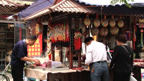 Люди выбирают традиционные сувениры в ларьке на торговой улице в китайском городе Сиань . — стоковое видео