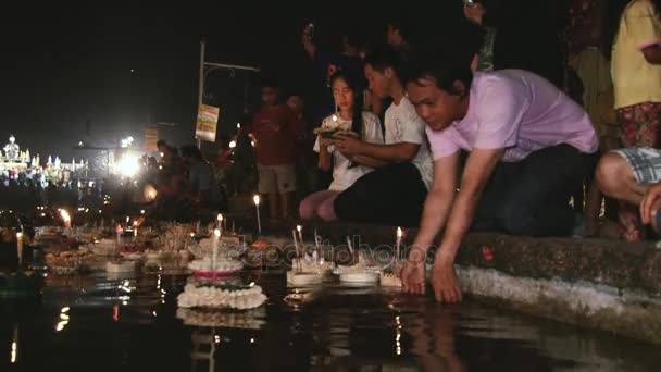 Люди молятся и ставят плавающие свечи на воду во время празднования Loi Krathong в Сукхотай, Таиланд . — стоковое видео