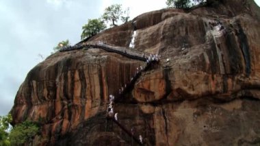 İnsanlar tırmanmaya ve eski Sigiria kaya kale Sigiriya, Sri Lanka kalıntıları ziyaret merdivenlerde inerler.