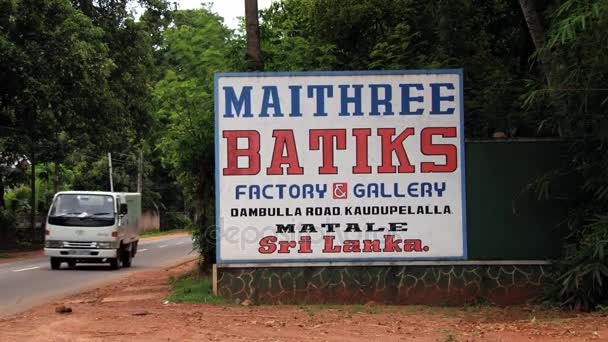 Auto's langs de weg met het teken van de batik fabriek in Kandy, Sri Lanka. — Stockvideo